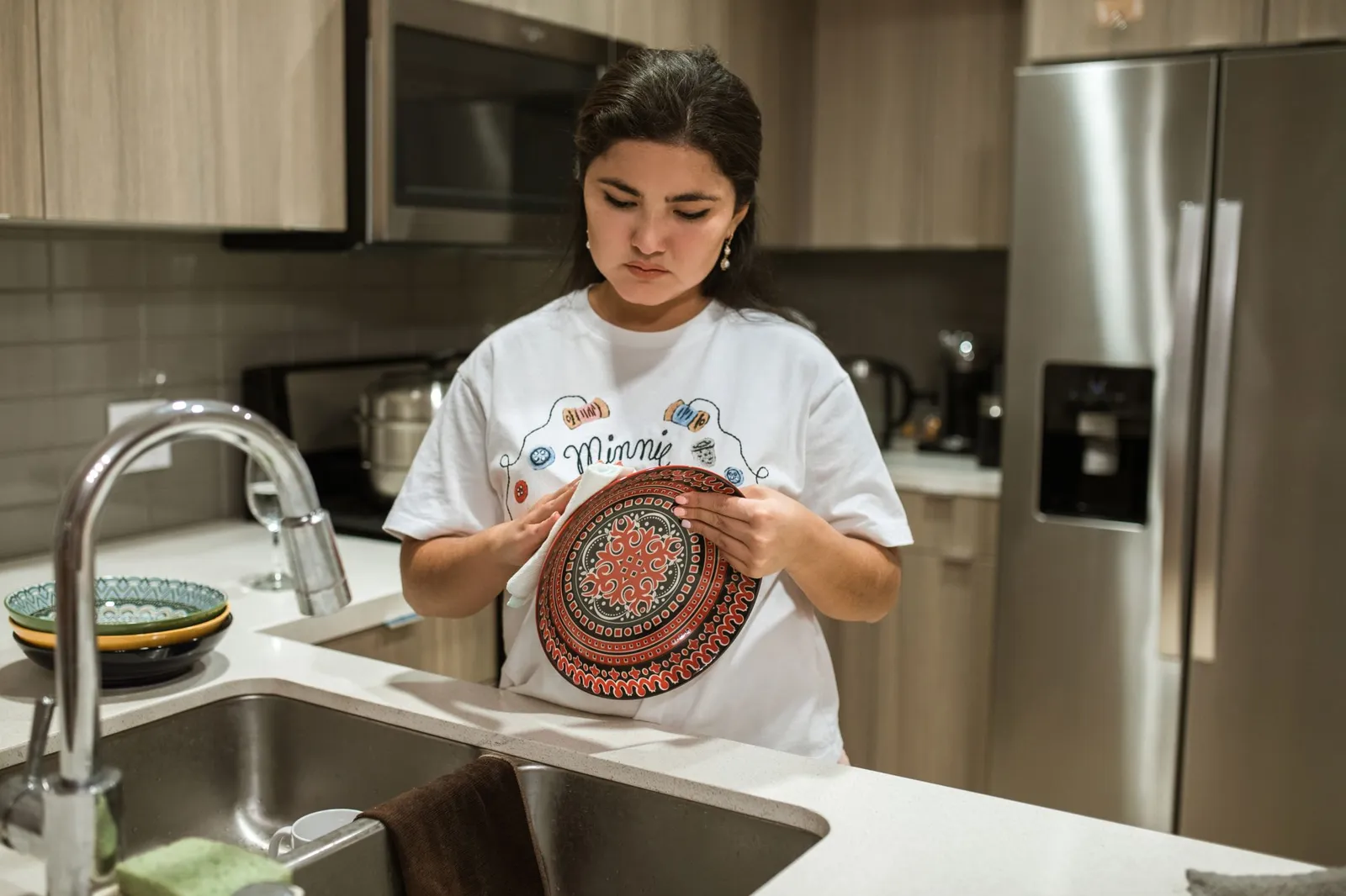 Une femme tient une assiette peinte dans sa cuisine