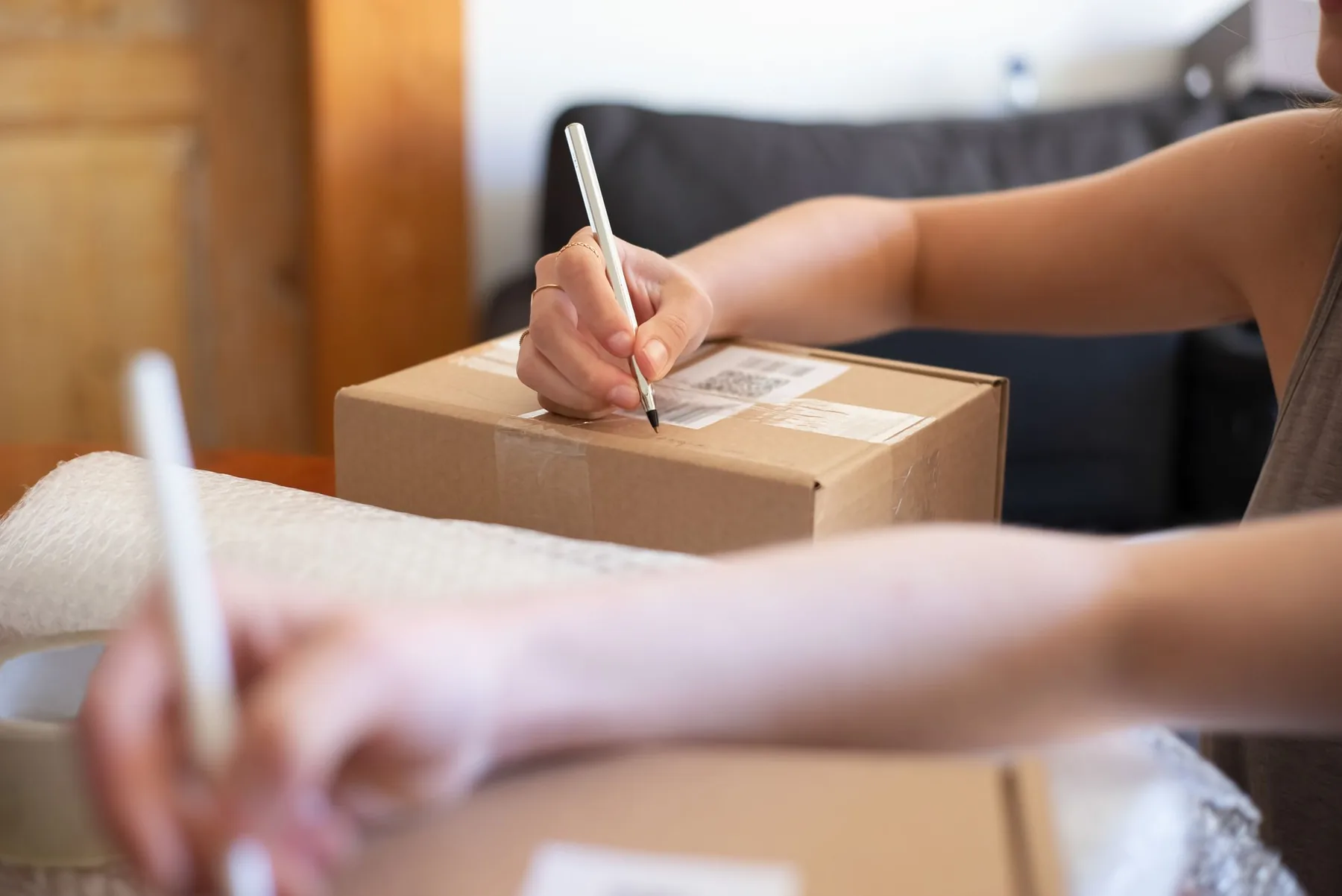 Une personne écrit une adresse sur un carton