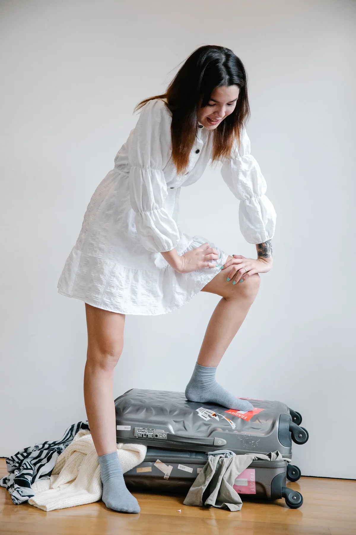 Une voyageuse debout sur sa valise trop pleine pour la fermer