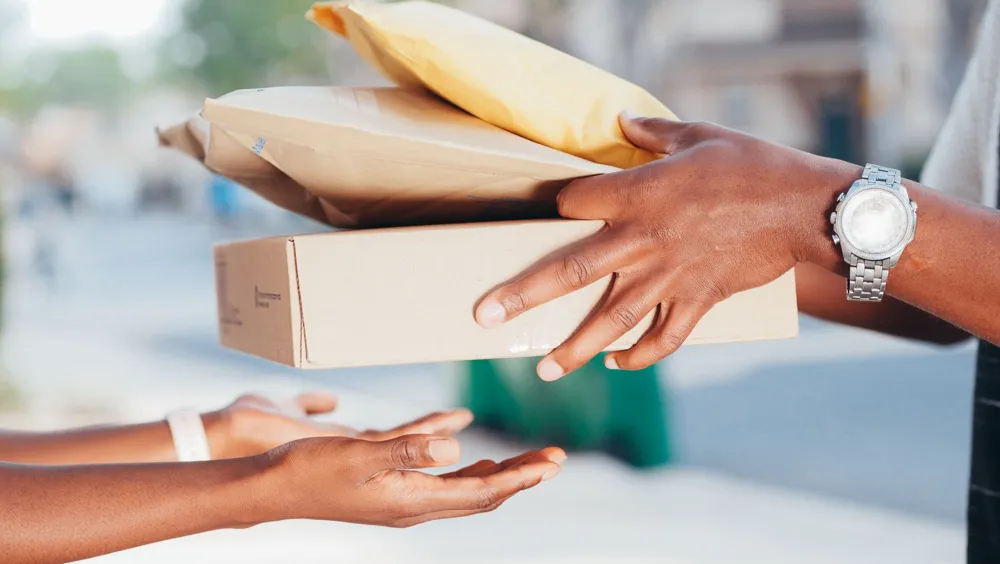 Des mains confient un colis en carton à une autre personne